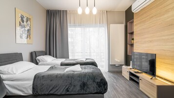 A modern hotel room with two beds, a flat-screen TV, a wooden cabinet, and a large window with curtains.