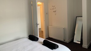 Un dormitorio con cama, un radiador, un espejo y una frase motivadora en la pared.