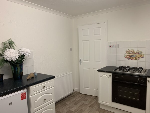 A kitchen with white cabinets, a black countertop, a gas stove, and a white door.