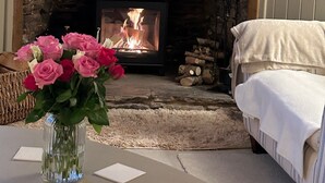A cozy room with a stone fireplace, a bed, and a vase of flowers.