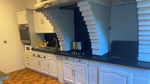 A kitchen with white cabinetry, a black countertop, and a tiled floor.