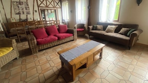 A living room with a wooden table, two sofas, and a wicker chair.