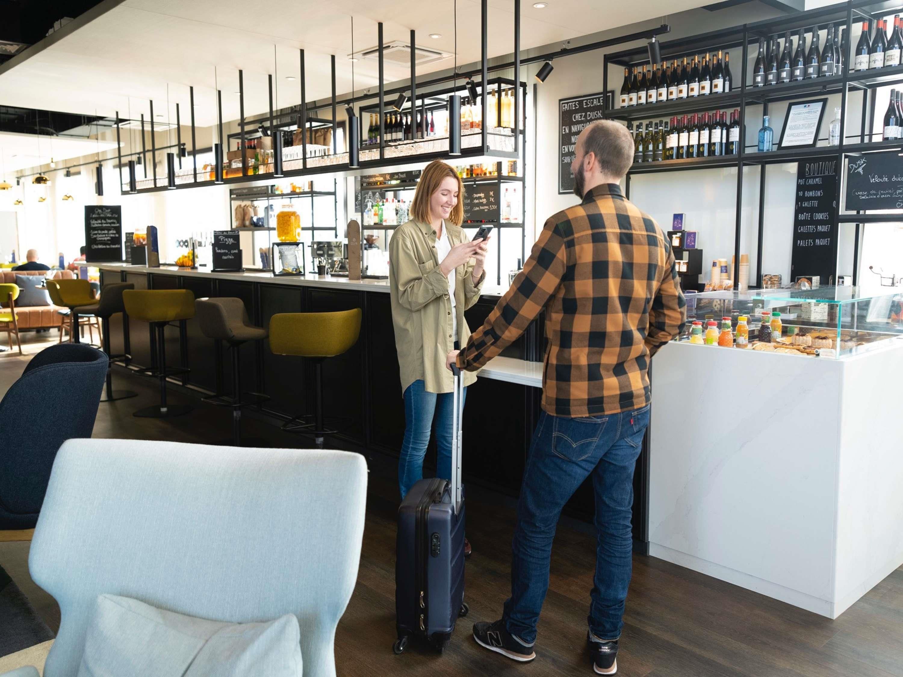 Un área de bar moderna con mostrador, taburetes y una exhibición de bebidas.
