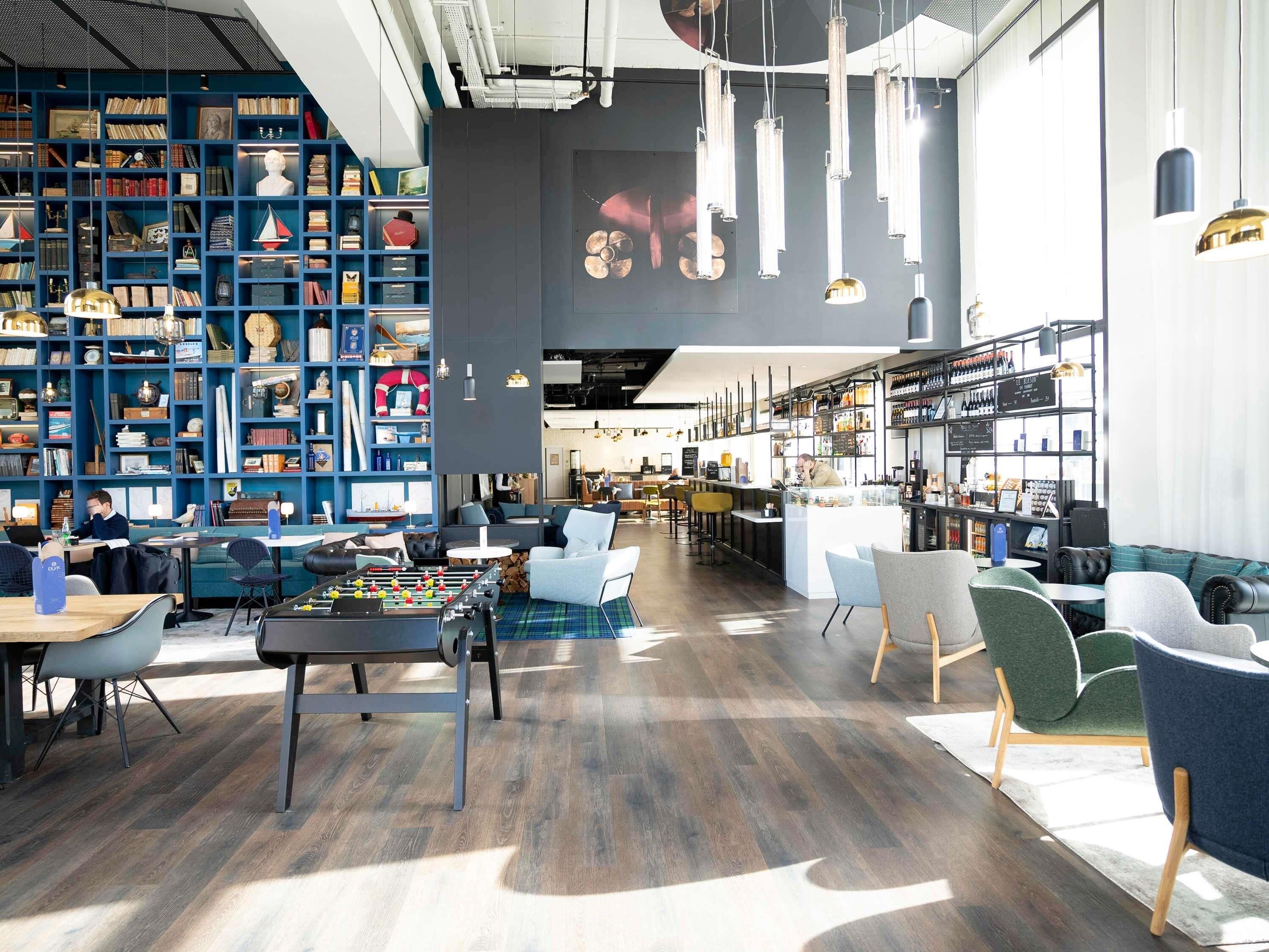 Una biblioteca moderna con estanterías, mesa de fútbol y zona de bar.