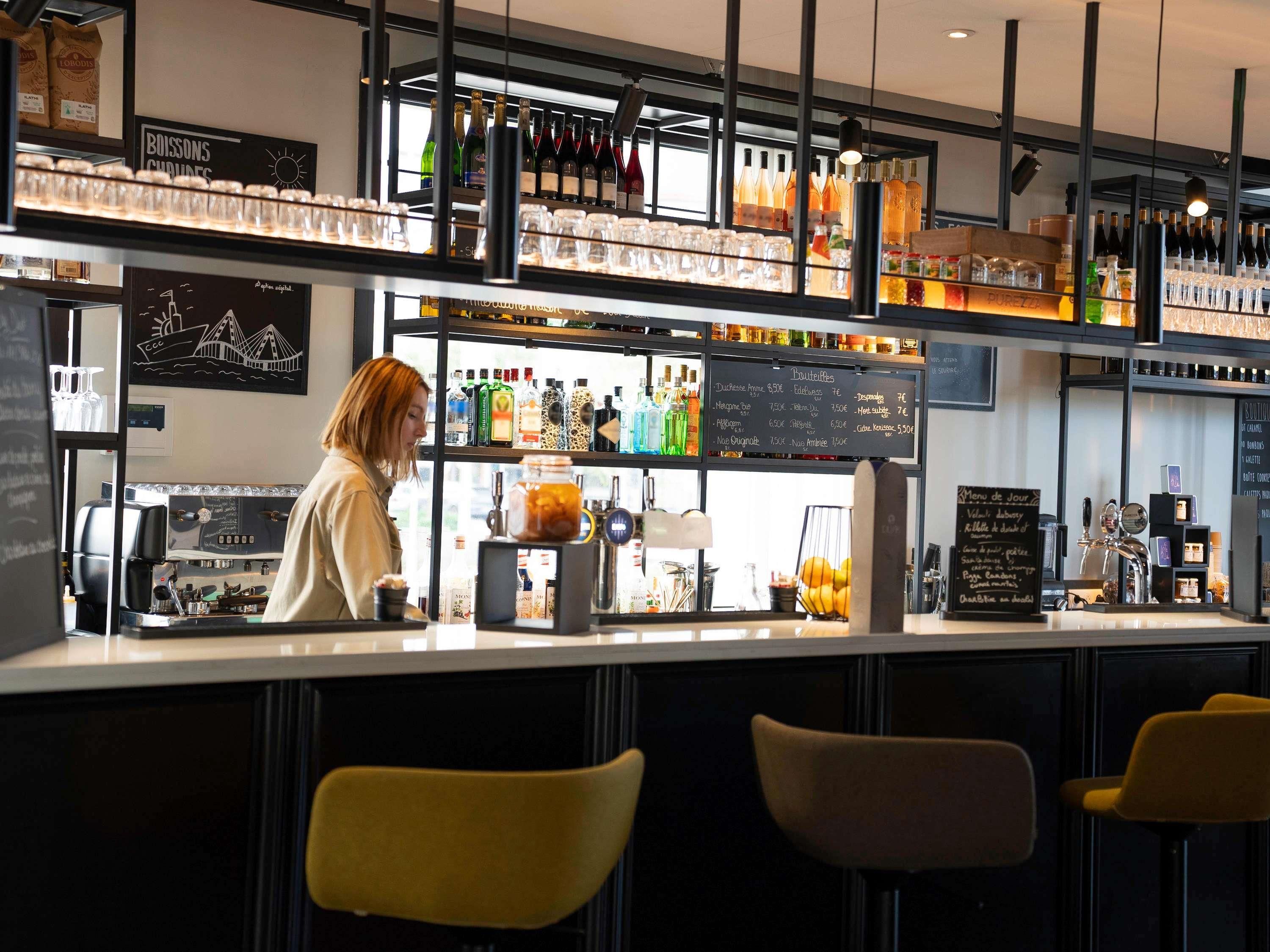 A bar area with a counter, shelves of bottles, and a menu board.