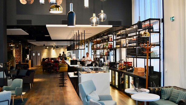 A modern bar area with seating, a bar counter, and a wine rack. - Ibis Budget Saint Nazaire Centre Gare (Saint-Nazaire)