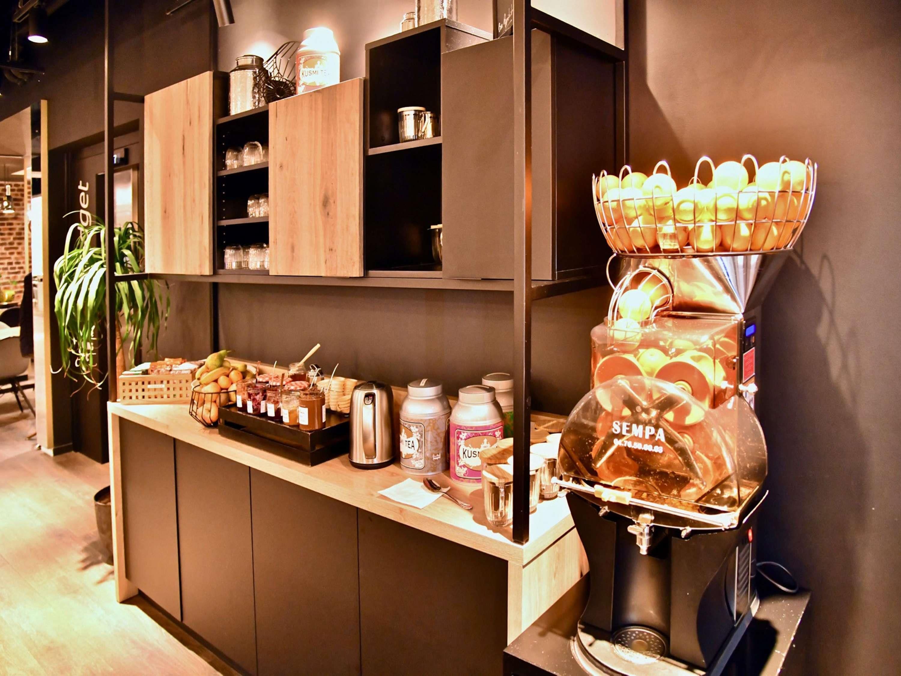 Una estación de café con una máquina de café, una cesta de manzanas y varios frascos de condimentos.