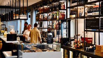 A well-lit bar area with shelves of various bottles and glasses, a cash register, and a menu board.