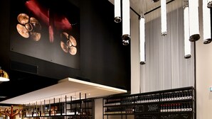 A modern bar area with a wooden floor, bar stools, and a wine rack. - Ibis Budget Saint Nazaire Centre Gare (Saint-Nazaire)