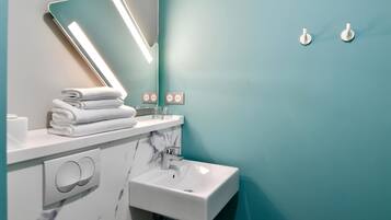 Une salle de bain avec un lavabo blanc, un miroir et un porte-serviettes.