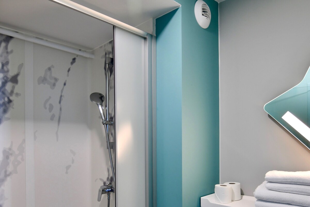 Une salle de bain moderne dotée d’une douche à parois de verre, de toilettes et d’un lavabo.