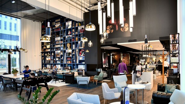 A modern indoor space with a foosball table, seating areas, and a large bookshelf. - Ibis Budget Saint Nazaire Centre Gare (Saint-Nazaire)