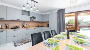 A modern kitchen with grey cabinets, a wooden countertop, and a dining area with a table set for six.