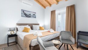 A hotel room with a bed, two chairs, a small table, a nightstand, and a window with curtains.