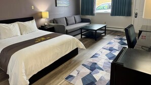 Una habitación de hotel con una cama, un sofá, una mesa de centro y un escritorio.