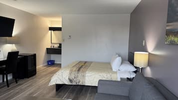 Een moderne hotelkamer met een bed, een bank, een bureau en een televisie.