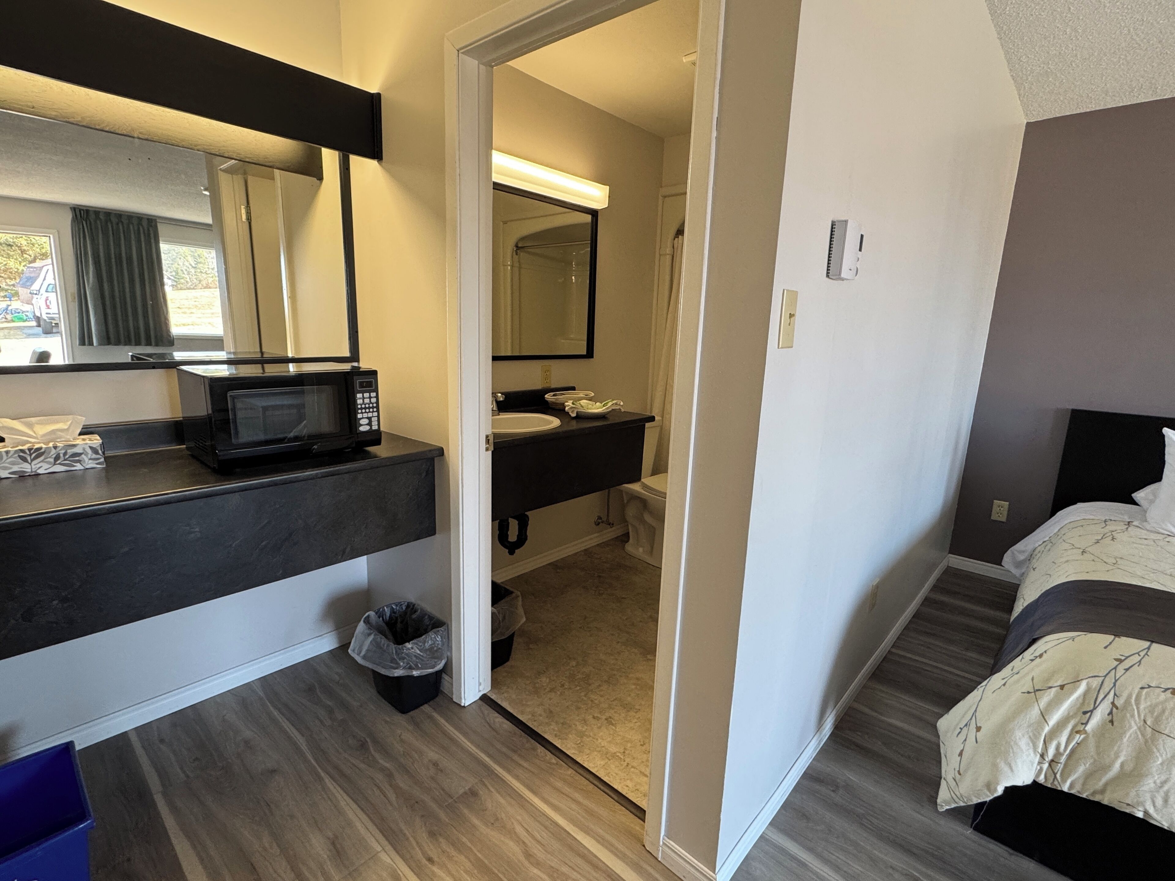 Een hotelkamer met een kitchenette, een badkamer en een bed.
