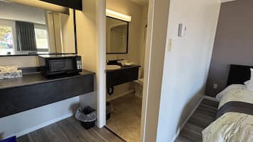 A hotel room with a kitchenette, a bathroom, and a bed.