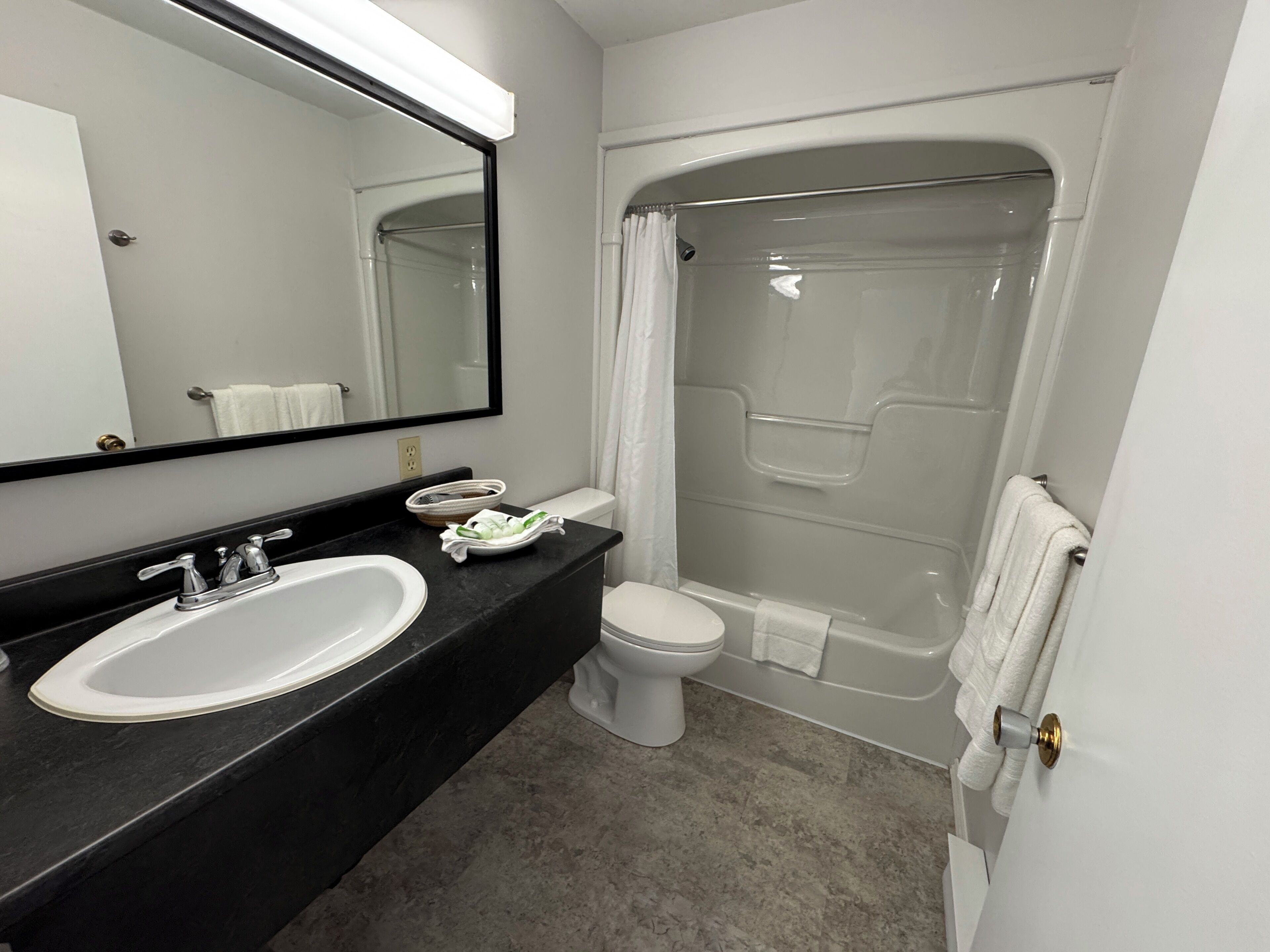 A modern bathroom with a black countertop, white sink, and toilet.