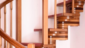Una scala in legno con una passerella rivestita di tappeto rosso.