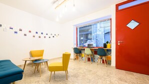 A room with a blue sofa, yellow chairs, a small table, a red door, and a window with a city view. - Via S Liborio - 6 Piano (Naples)