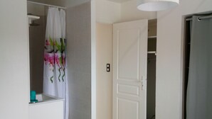 Une chambre à coucher avec un lit, une salle de bain avec un rideau de douche et un placard.