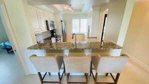 A kitchen with a central island, bar stools, and modern appliances.