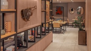 Un interior moderno con una estantería de madera, una guitarra y un comedor con sillas y mesas.