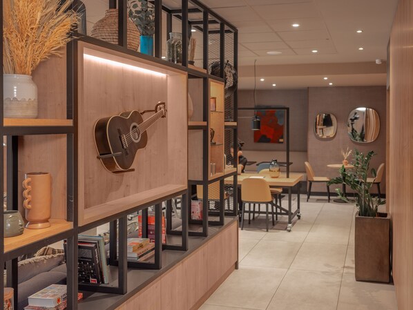 Un interior moderno con una estantería de madera, una guitarra y un comedor con sillas y mesas.