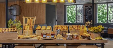 A breakfast buffet with various pastries, bread, and fruits.