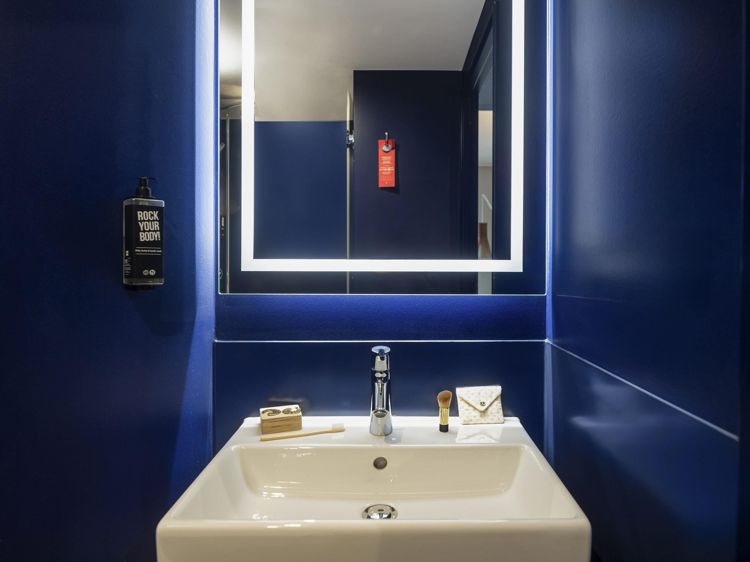 Un baño con un lavamanos blanco, un espejo y una pared azul.