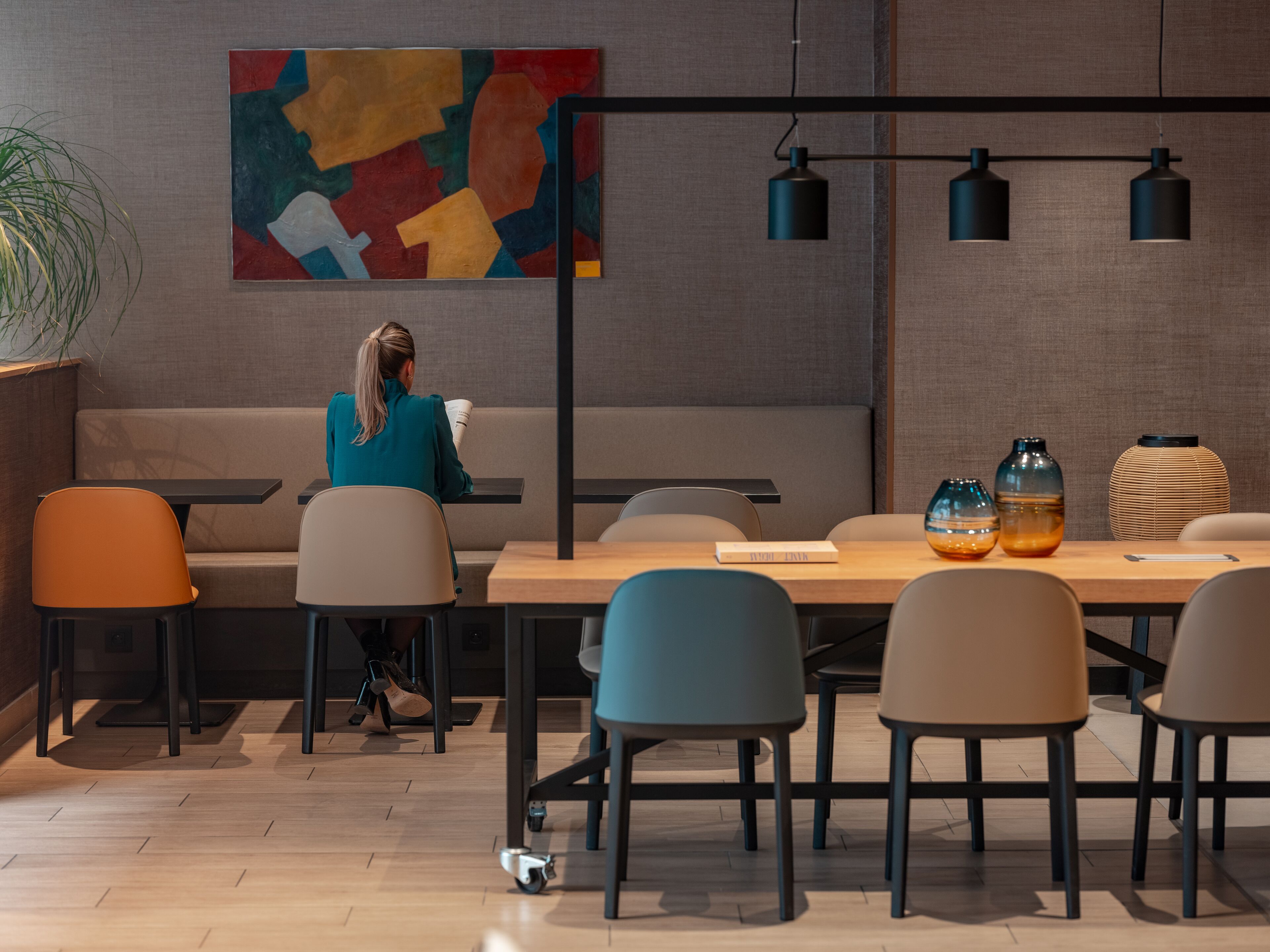 A modern interior with a sofa, dining table, chairs, and a large abstract painting.