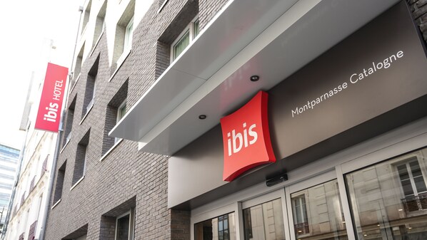Fachada de hotel con letrero que dice 'ibis HOTEL' y el texto 'Montparnasse Catalogue'.