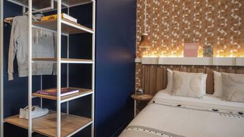 Un dormitorio con una cama, un armario con estantes y una pared con estampado.