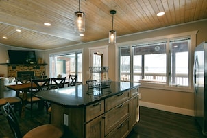 A modern kitchen with wooden cabinets, a central island, and pendant lighting.