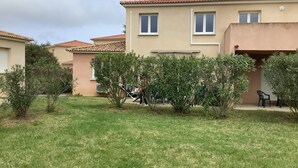 Um edifício residencial com telhado ladrilhado, várias janelas e um gramado bem cuidado.