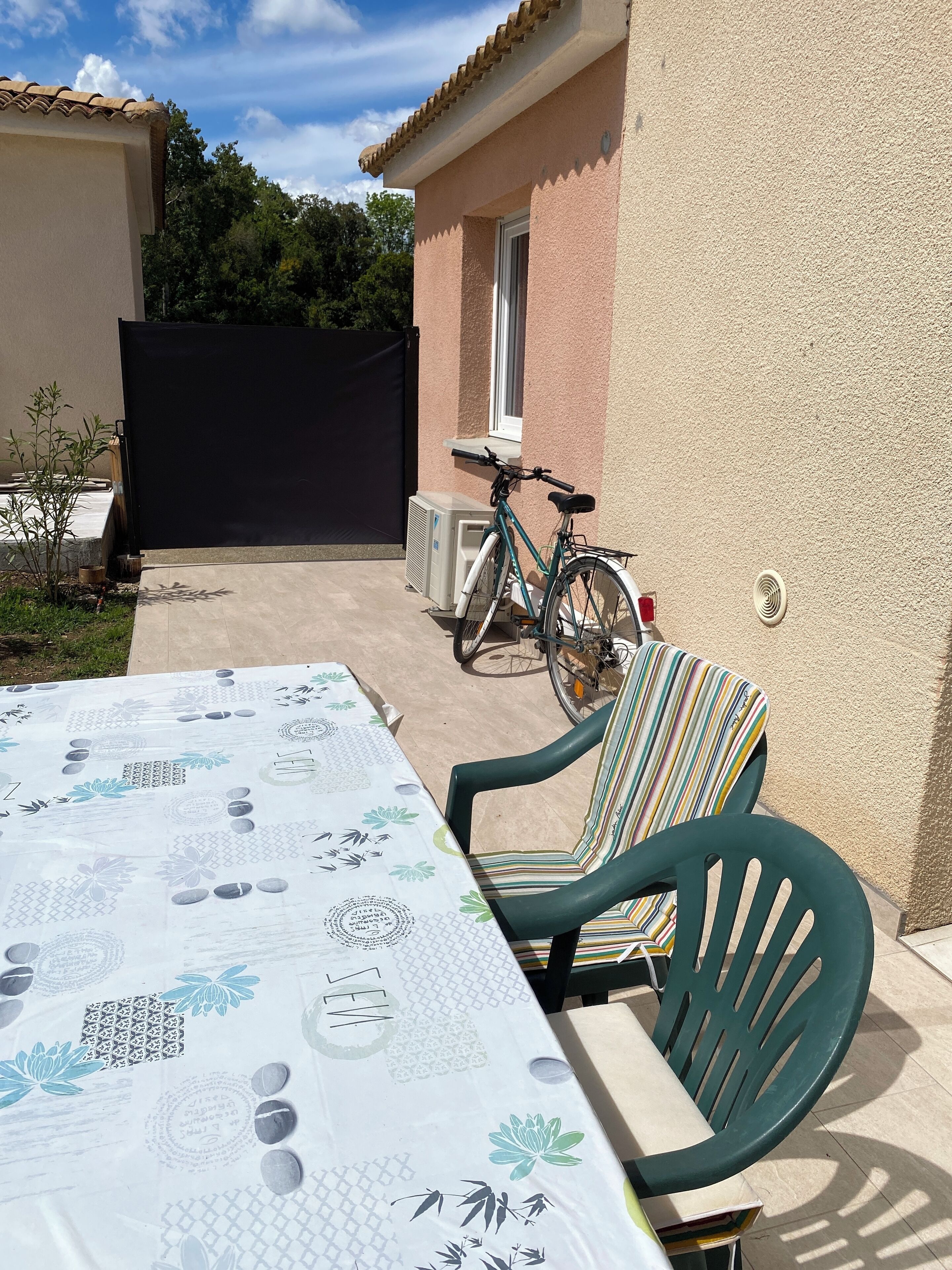En udendørs terrasse med spisebord, en cykel og en stol.
