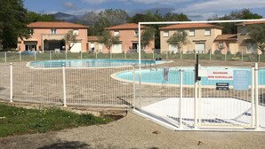 Uma área de piscina cercada por edifícios com um estilo arquitetônico uniforme.