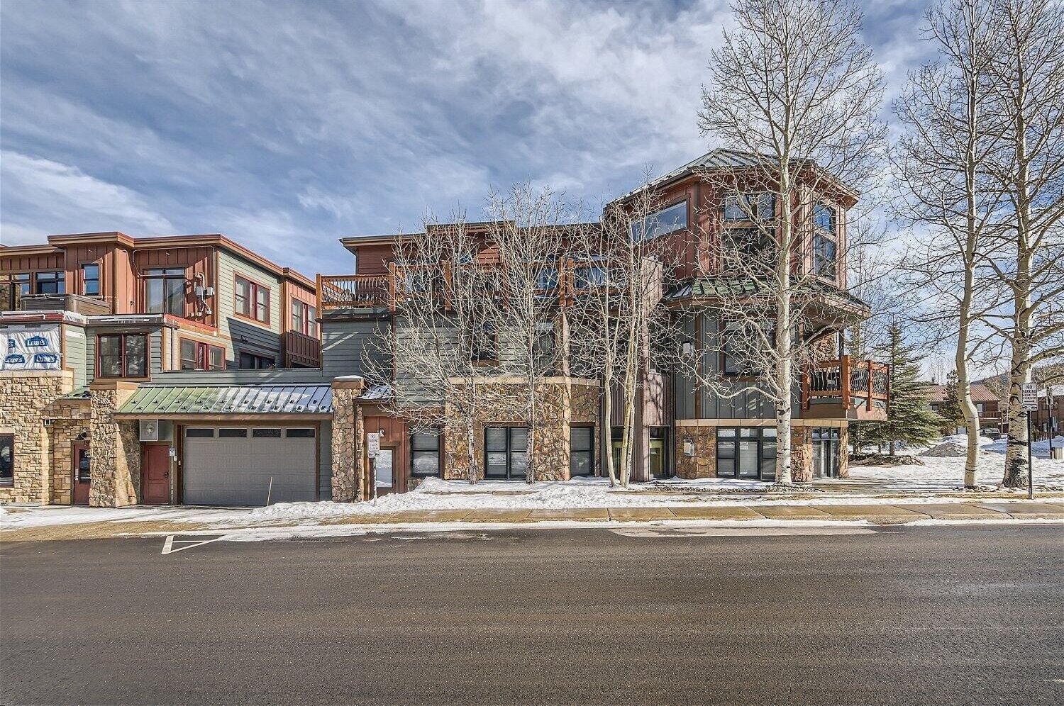 A multi-story building with a stone facade, multiple windows, and a garage.