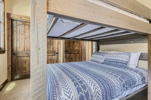 A bunk bed with a patterned bedspread, wooden door, and exposed ceiling beams. - Condos Off Main 15 4 Bedroom Condo by RedAwning (Frisco)