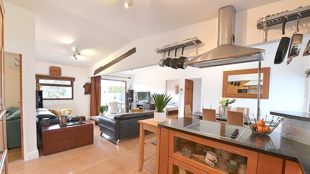 A modern kitchen with a central island, wooden cabinets, and a stainless steel range hood. - Gorgeous 3BD Cottage in the Heart of Guildford (Guildford)