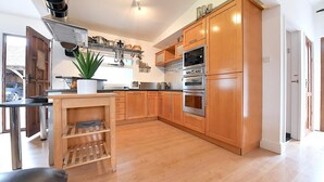 A modern kitchen with wooden cabinets, stainless steel appliances, and a central island. - Gorgeous 3BD Cottage in the Heart of Guildford (Guildford)