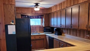 A kitchen with wooden cabinets, a black refrigerator, a microwave, and a wooden countertop. - Cavalier # 2 3 Bedroom Townhouse by RedAwning (Cable)
