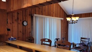 A wooden interior with a long dining table, chairs, a clock, and pendant lights. - Cavalier # 2 3 Bedroom Townhouse by RedAwning (Cable)
