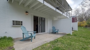 Une maison blanche dotée d’un patio couvert, de deux fauteuils Adirondack et d’une porte-fenêtre coulissante.