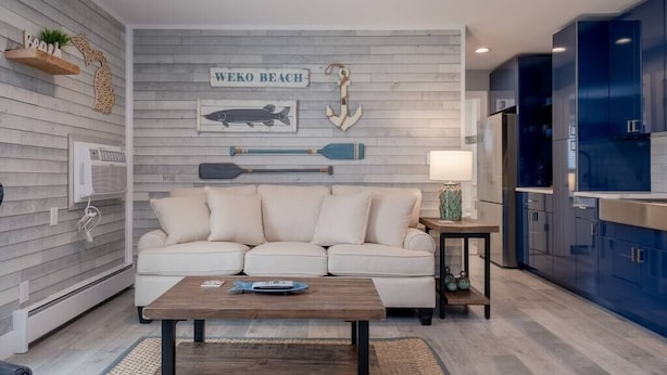 Un salon moderne avec un canapé blanc, une table basse en bois et des éléments de décoration murale sur le thème de la marine.