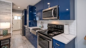 Une cuisine moderne avec des armoires bleues, des appareils en acier inoxydable et un comptoir blanc.