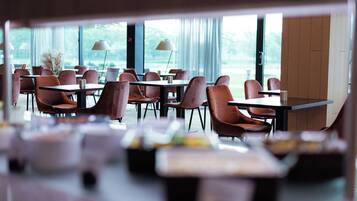 A modern restaurant with tables and chairs arranged for dining.