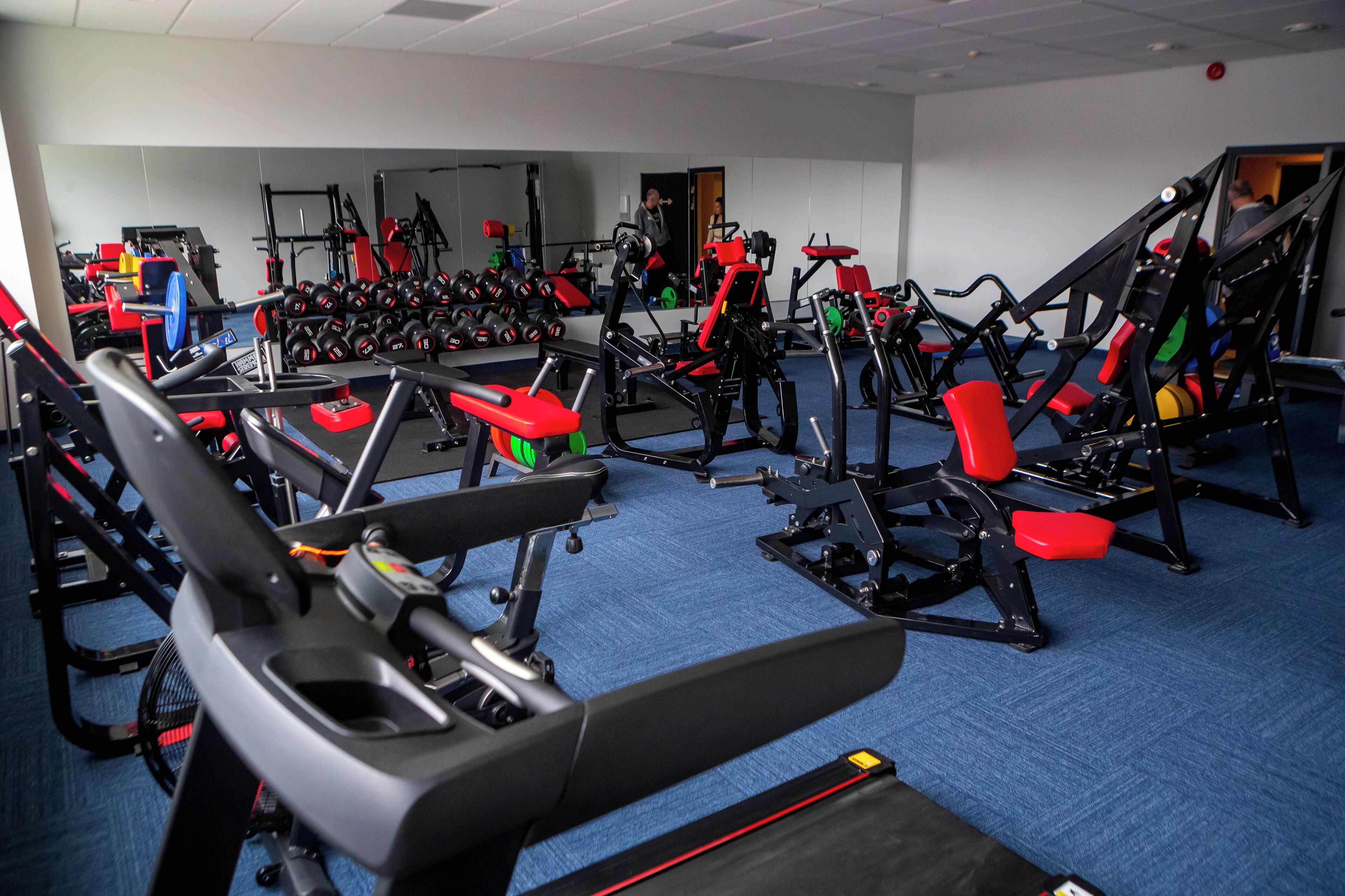 A gym with various exercise equipment, including treadmills, weight machines, and free weights.