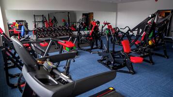 A gym with various exercise equipment, including treadmills, weight machines, and free weights.